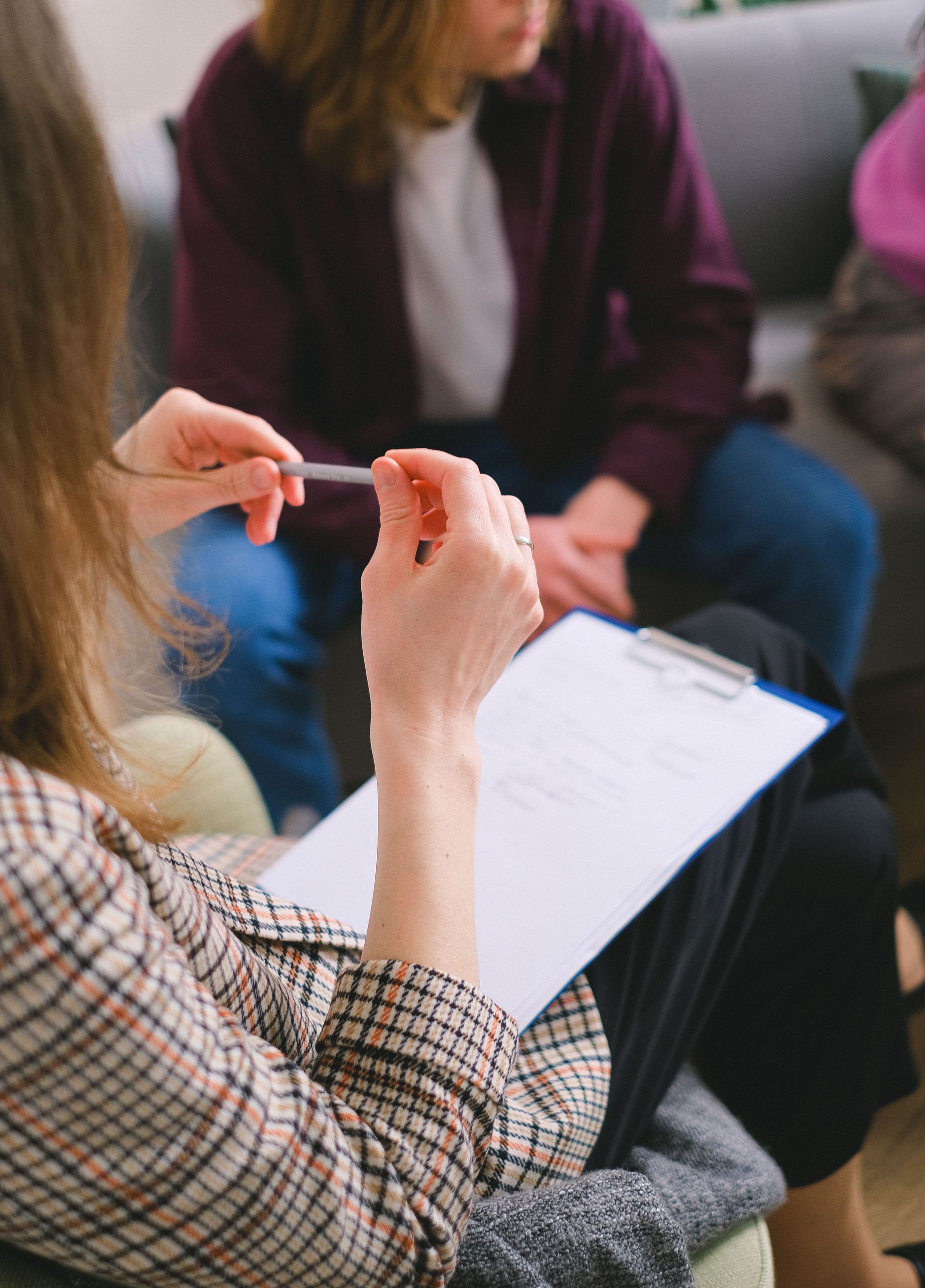 A therapist with a clipboard conducting a counseling session with clients.