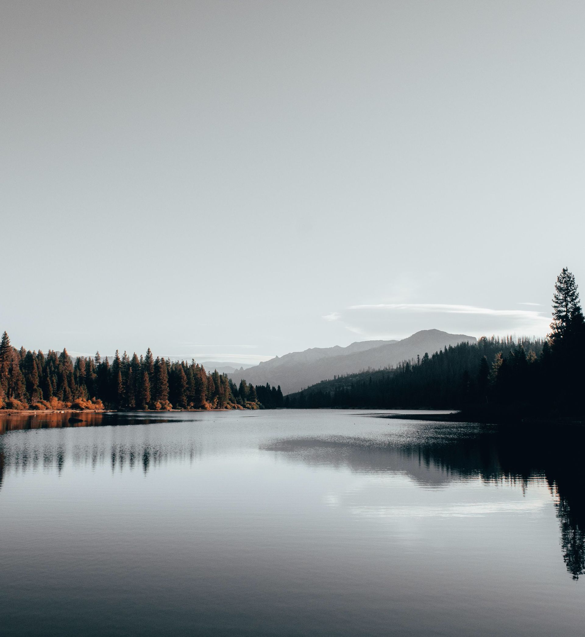 Serene lake with mountains and trees reflected in the water, perfect for nature lovers.