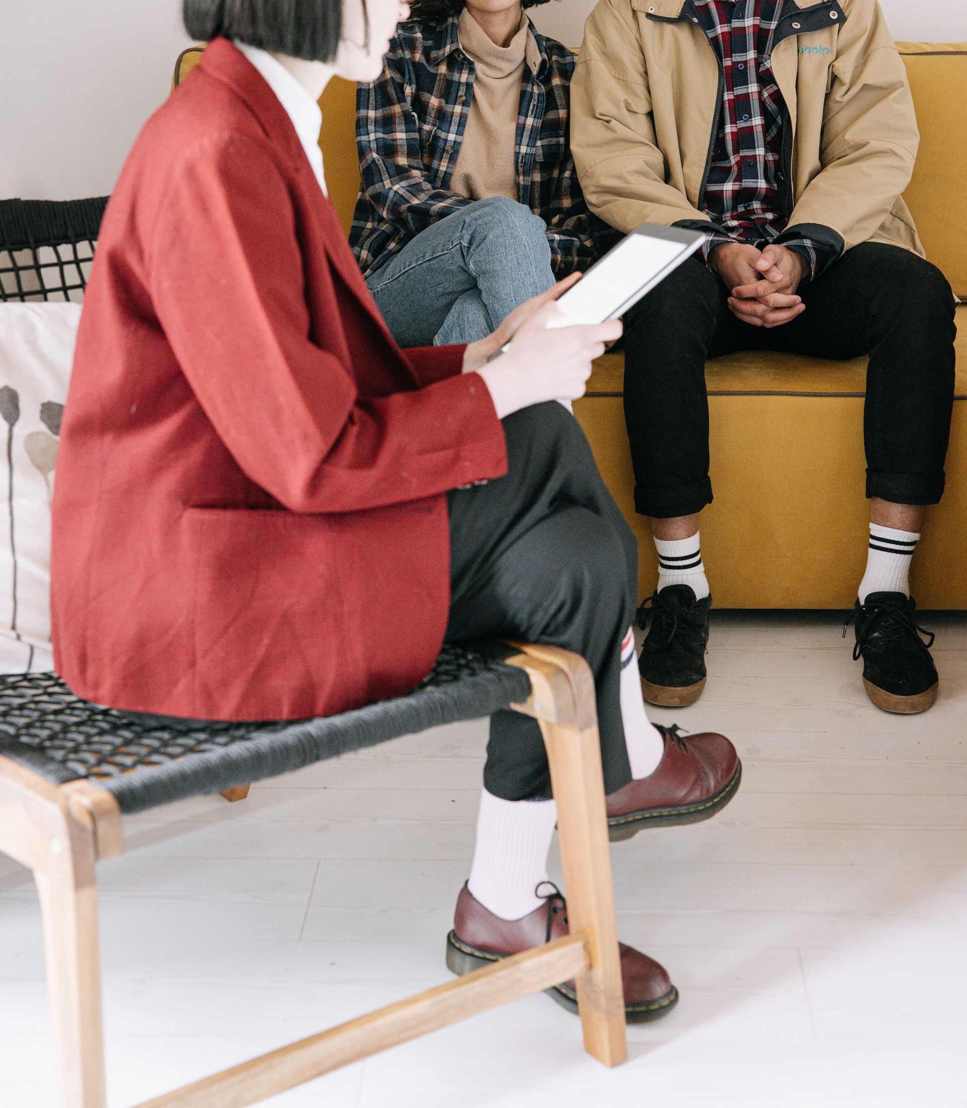 A therapist leads a counseling session with a young couple seated on a couch.